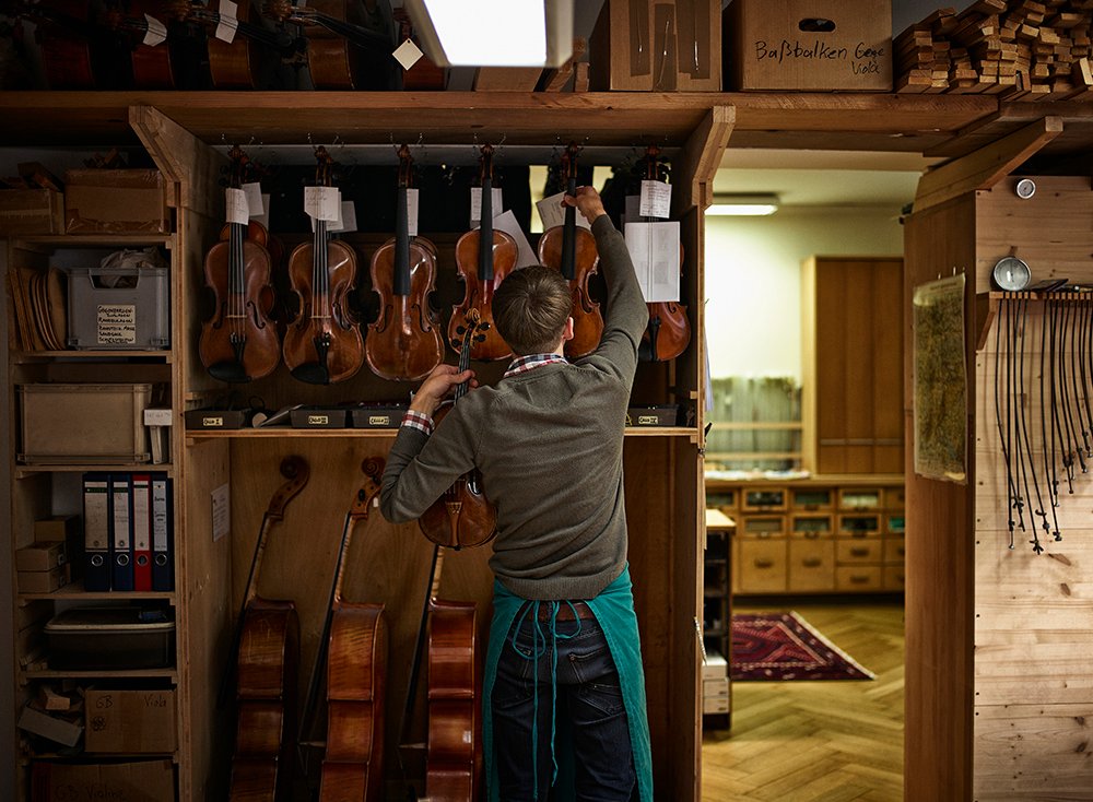 Violin maker in his workshop with restored violins